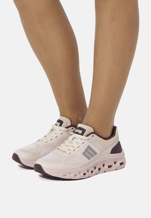 Zapatillas deportivas ligeras en beige con una parte superior de malla texturizada, acentos en púrpura oscuro y una suela acolchada rosa con ventilaciones de aire.