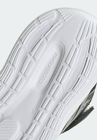 Vit gummisul med räfflad yta, med "CLOUDFOAM" präglat i en cirkulär yta och mönstrade greppkanaler.