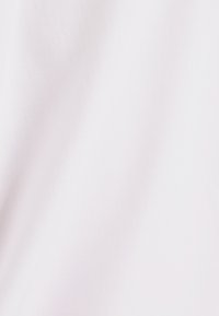 Gładka biała tkanina o jednolitej fakturze i subtelnym skośnym wzorze tkackim widocznym w miękkim świetle.