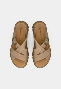 Beige sandals with cross-over fabric straps, a textured surface, and a bronze buckle accent. Cushioned footbed and durable sole. Size 4½.