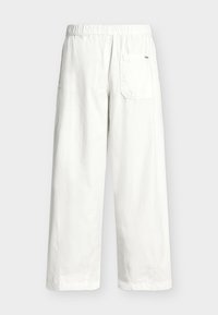 Λευκό χαλαρό παντελόνι με ελαστική μέση και μία πίσω τσέπη, εμφανίζεται από πίσω σε μονόχρωμο φόντο.