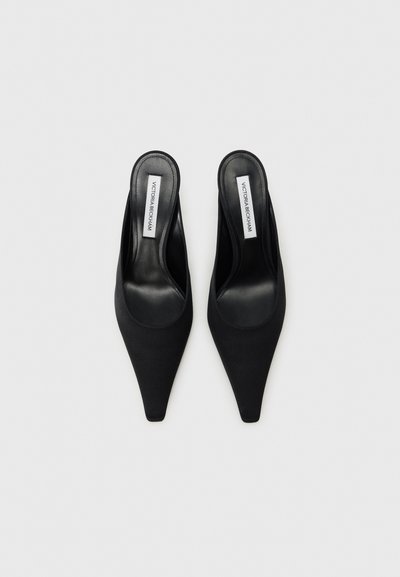 Μαύρα υφασμάτινα mules με μυτερή μύτη και ανοιχτή πίσω σχεδίαση. Λείος δερμάτινος πάτος και ετικέτα με το λογότυπο ορατή στη φτέρνα.