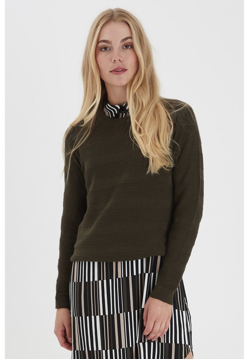Olivgrüner Rundhals-Pullover mit strukturierten horizontalen Streifen, kombiniert mit einem schwarz-weißen gestreiften Rock mit unterschiedlichen Breiten.