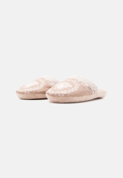 Ταν παντόφλες από ύφασμα με λευκό ανθικό σχέδιο, απαλό εσωτερικό από γούνα και ανυψωμένο σχεδιασμό στα δάχτυλα. Στυλ που φοριέται εύκολα χωρίς πίσω μέρος.