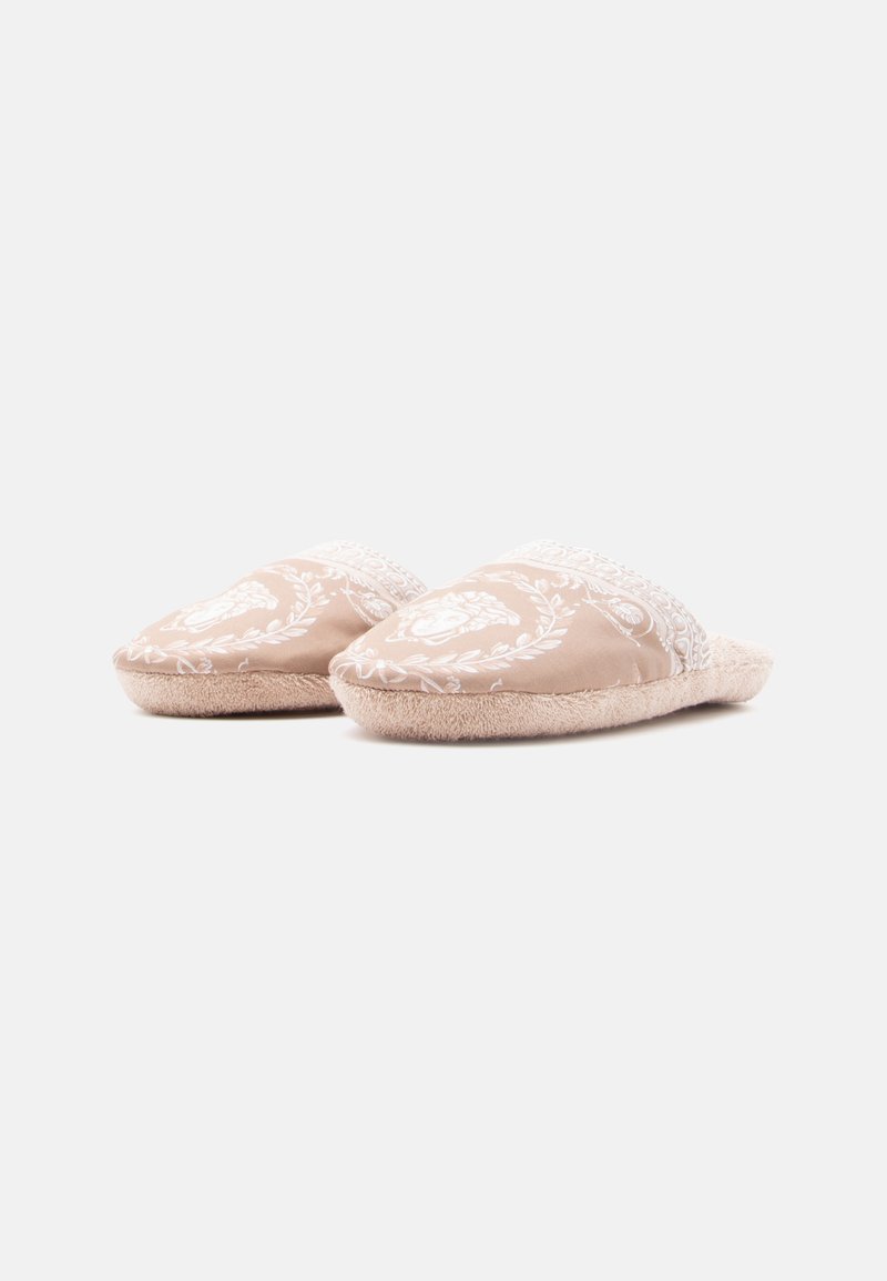 Tanfarvede tøfler med hvidt blomsterprint, blød pelsforing og en forhøjet tådesign. Slip-on-stil uden bagstykke.