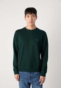 Donker groene sweatshirt van katoen, met lange mouwen, een ronde hals, geribbelde manchetten en een klein logo-embleem op de borst.