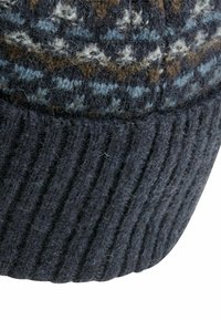 Strikket uldbeanie med en ribbet mørkeblå kant, der har et mønster i nuancer af blå, brun og creme øverst.
