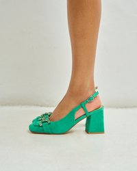 Des escarpins en suède vert avec une empeigne à sangle présentent un bout carré et un talon bloc épais. Décorés d'accents décoratifs à l'avant pour une touche de détail supplémentaire.