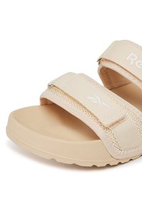 Beżowe sandały na platformie z dwoma regulowanymi paskami z tkaniny, teksturowaną podeszwą i subtelnym logo na paskach. Wykonane z elastycznych, lekkich materiałów.