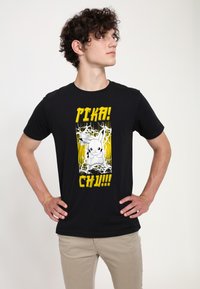 Černé bavlněné tričko s grafikou kreslené postavy s žlutými, bílými a černými akcenty, textem "PIKA! CHU!!!" kolem ní.