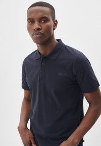Námornícky polo tričko vyrobené z bavlny, s trojitou gombíkovou légou, krátkymi rukávmi a jemným logom na ľavej hrudi.