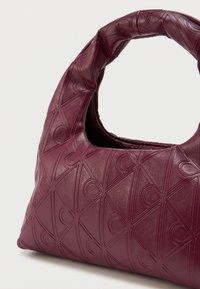 Bordeauxfarvet, struktureret læderhåndtaske med et afrundet håndtag og præget geometrisk mønster. Kompakt form med en struktureret silhuet.
