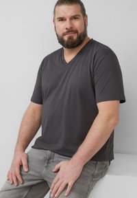 Donkergrijze V-hals T-shirt met korte mouwen, gemaakt van een soepele stof. Subtiele logodetail op de borst. Casual pasvorm, gecombineerd met grijze jeans.