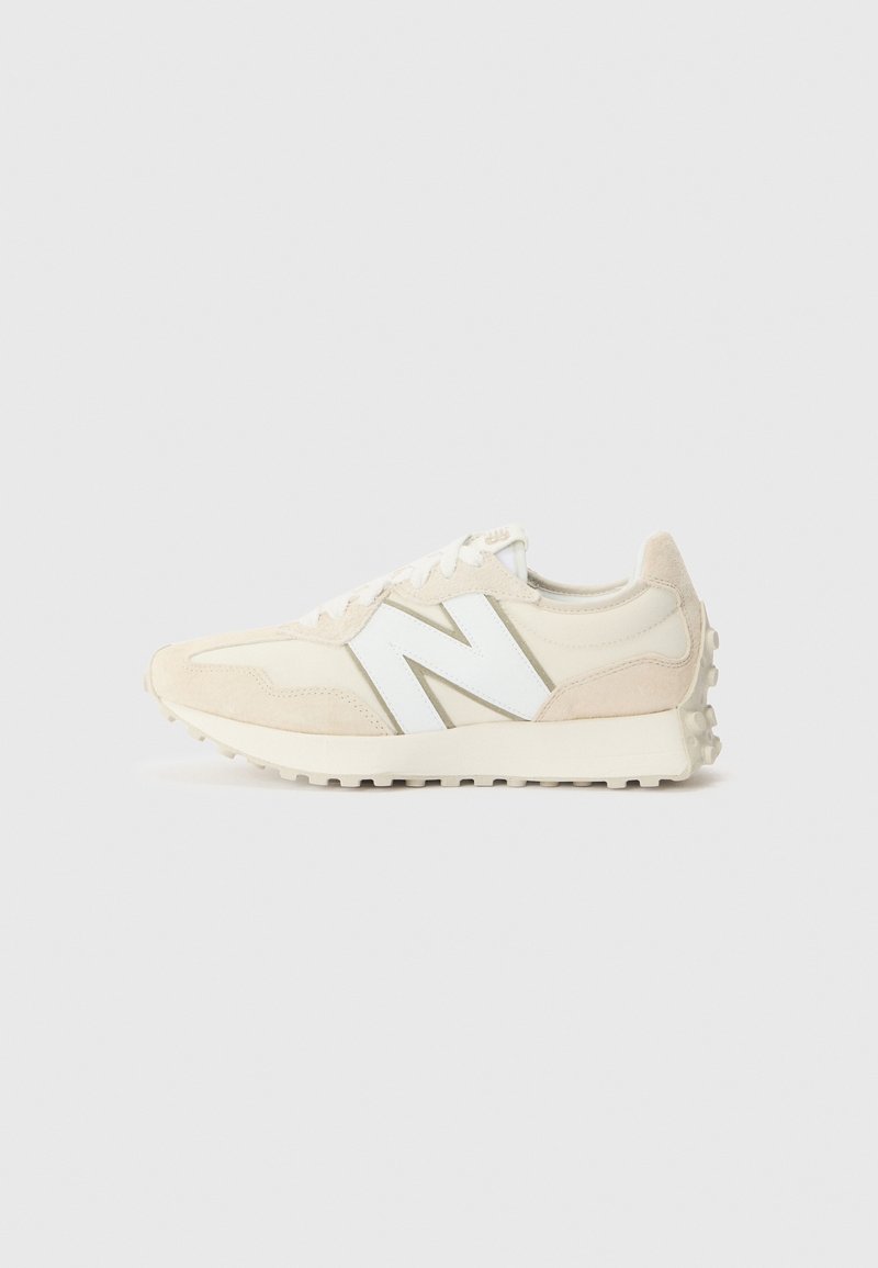 Baskets New Balance beige et blanches avec accents en suède, grand logo blanc "N" sur le côté, semelle texturée et fermeture à lacets.