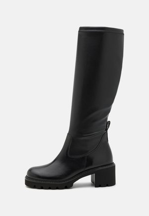 Bottes noires montantes en cuir lisse, avec un talon bloc épais et une semelle texturée. Équipées d'une fermeture éclair sur le côté pour un enfilage facile.