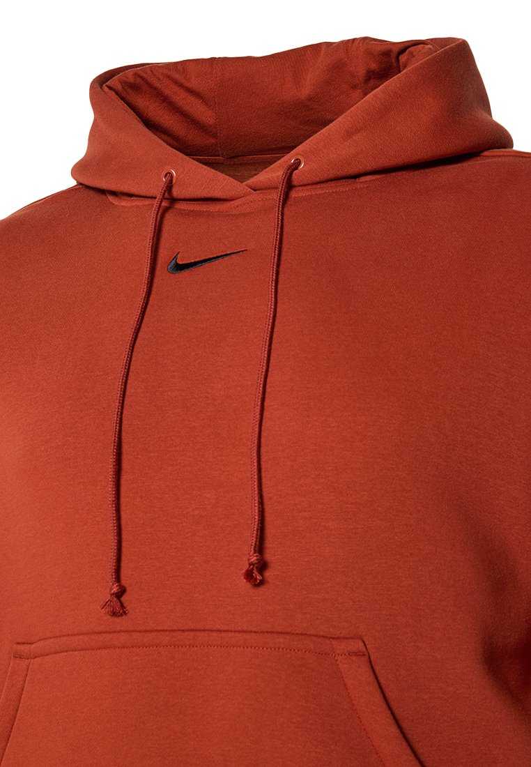 Nike huvtröja i rostfärg, med en känguruficka, dragsko med metallspetsar och en liten svart logotyp på bröstet.