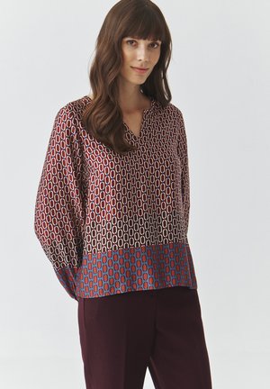 Langsleeve blouse in bordeaux met geometrisch patroon; met een v-hals en een blauwe zoom, zijdezachte textuur en een relaxte pasvorm.