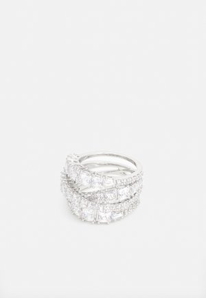 Tres anillos apilados hechos de plata con múltiples piedras claras y brillantes de forma rectangular y redonda, dispuestas en un diseño curvado.