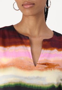 Abito multicolore con scollatura a V, caratterizzato da strisce orizzontali in tonalità di rosso, rosa, arancione e verde, realizzato in tessuto morbido.