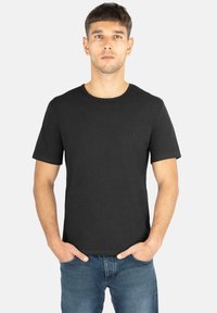 Schwarzes Baumwoll-T-Shirt mit kurzen Ärmeln, rundem Ausschnitt und einem kleinen Logo-Detail auf der Brust. Glatte Textur, taillierte Passform.
