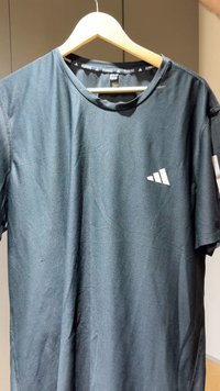 Melnā sporta T-krekls no elpojoša auduma ar teksturētu virsmu. Tas ir ar apaļas formas kakla izgriezumu un baltu logotipu ar trim diagonālām svītrām.