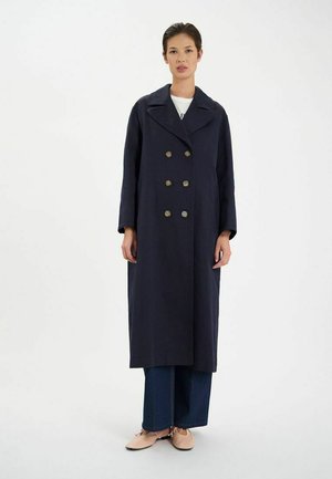 Manteau long bleu marine à double boutonnage, grand col en V et cinq boutons ronds. Fabriqué en tissu texturé, il possède des manches larges.