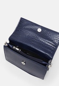 Granatowa torba ze skóry tłoczonej w wzór krokodyla, z kieszenią na zamek, magnetycznym zatrzaskiem oraz eleganckimi srebrnymi akcesoriami.