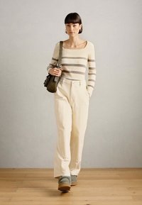 Striped sweater in beige and gray, cream wide-leg pants, gray footwear, and a small green bag. Simple design with a classic fit.