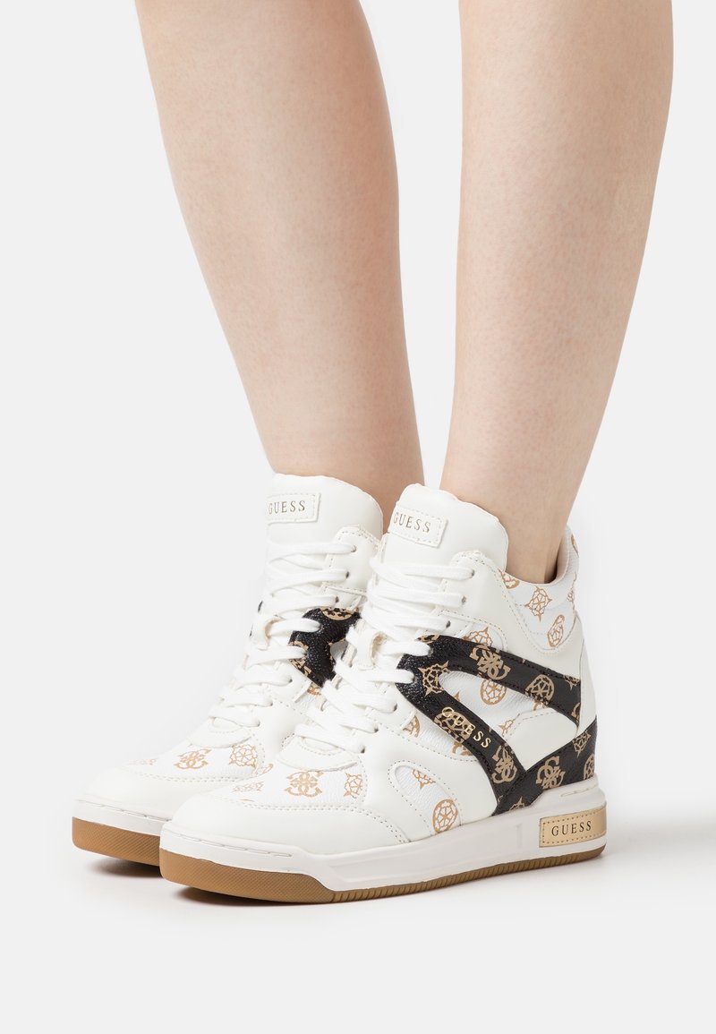 Białe sneakersy typu high-top z złotym wzorem logo, czarnymi akcentami i teksturowaną gumową podeszwą. Związane z przodu.