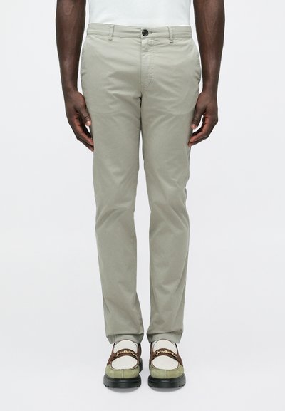 Chino slim fit grigio chiaro con una texture liscia e tasche frontali, abbinati a sneakers multicolori con un dettaglio decorativo a catena.