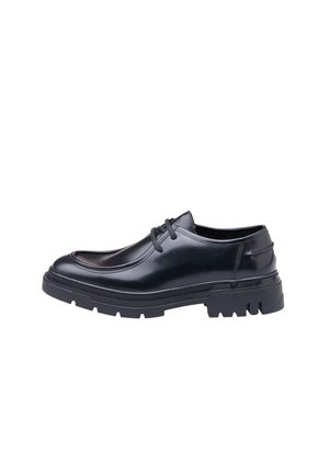 Schwarzer Lederschuh mit abgerundeter Zehenpartie, Schnürdesign und einer dicke, strukturierten Gummisohle mit tiefen Rillen für verbesserten Halt.