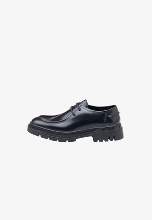 Chaussure en cuir noir avec un bout rond, un design à lacets et une semelle en caoutchouc épaisse et texturée dotée de profondes rainures pour une meilleure traction.