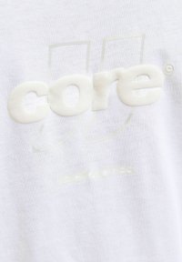 Fehér pamut póló, enyhén kiemelkedő, texturált "core" logóval és kisebb méretű "jack & jones" felirattal megegyező fehér árnyalatban.