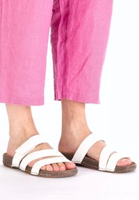 Witte leren slip-on sandalen met drie brede banden, met een gestructureerde bruine zool. Draagt met losse, roze cropped pants.