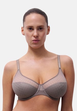 Transparenter beiger BH mit geometrisch gemusterten Einsätzen, verstellbaren dünnen Trägern und einer glatten Oberfläche auf den Cups.