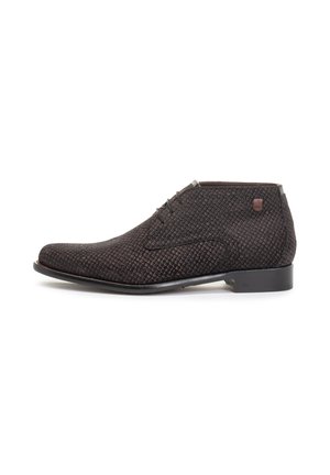 Bottine en cuir texturé marron foncé avec un bout carré, trois œillets et un petit logo sur le côté. Semelle en caoutchouc lisse.