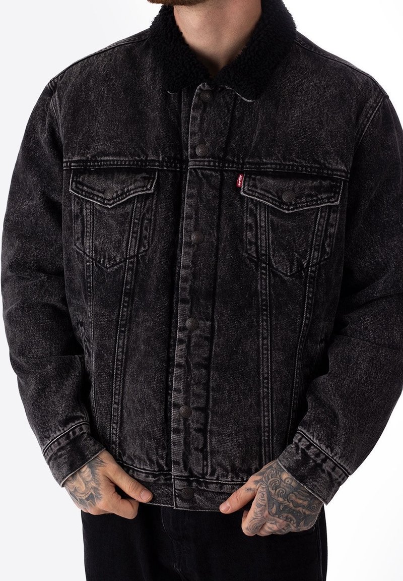 Svart denimjacka med en texturerad sherpa-krage, med frampengar, knappstängning och en blekt tvätt för en sliten look.