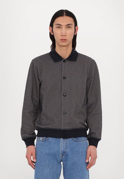 Giacca a maglia con motivo testurizzato in blu navy e crema, caratterizzata da un collo allacciato, chiusura frontale con bottoni e polsini e orlo a costine.