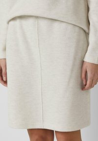 Gebreide crèmekleurige rok met een rechte vorm, subtiele textuur en een nette centrale naad aan de achterkant voor extra designdetail.