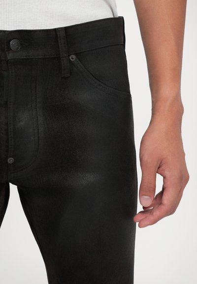 Jeans in denim nero con una vestibilità slim, caratterizzati da una leggera lucentezza, cinque tasche e una chiusura con bottone. Il tessuto presenta una leggera trama.