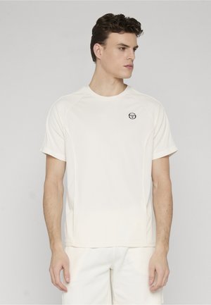 Ung mand iført en ensfarvet hvid t-shirt med korte ærmer og et lille sort logo på venstre bryst, vendt mod højre på en lys baggrund.