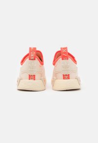 White and coral Adidas sneakers featuring a textured sole, padded collar, and printed heel tags. Soft fabric with a lightweight design.