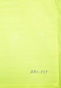 Jasnożółta tkanina Dri-FIT o teksturowanej powierzchni, z subtelnym paskowanym wzorem i nadrukowanym logo. Lekka i odprowadzająca wilgoć.