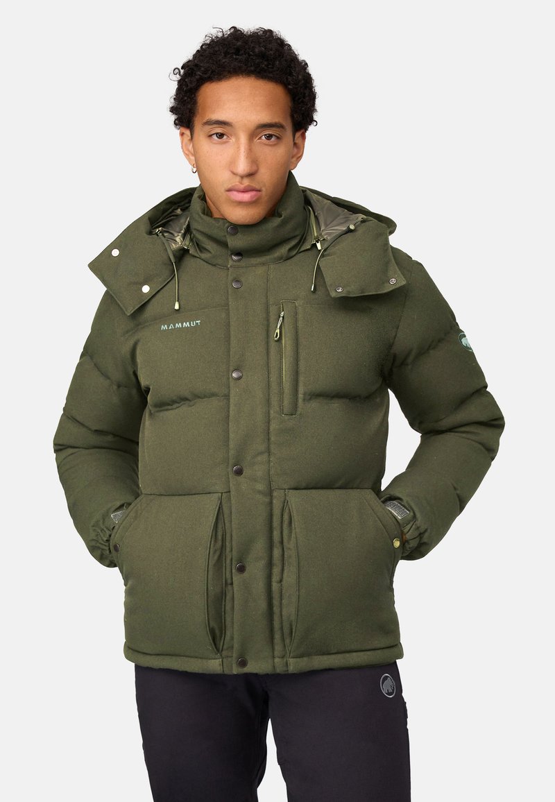 Grøn dynejakke med høj krave, flere lommer og knaplukninger. Har et tekstureret stof og justerbar snøre til hætten.