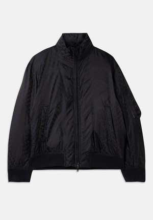 Chaqueta bomber negra hecha de un tejido suave y ligero. Presenta un collar alto, cierre frontal y bolsillos laterales. Patrón de logo sutil en toda la prenda.