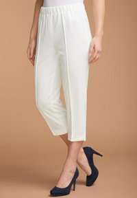 Witte, geplooide cropped broeken met een elastische tailleband, kenmerkend door een gladde textuur, gecombineerd met donkerblauwe hakken op een neutrale achtergrond.