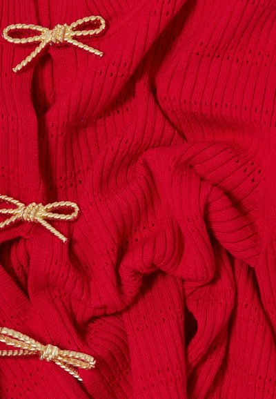 Tessuto a maglia rossa con coste verticali e piccoli fori, decorato con tre fiocchi dorati attorcigliati come dettagli decorativi.
