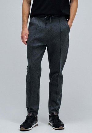 Graue Jogginghosen aus einem weichen, strukturierten Stoff, mit einem Kordelzugbund, schlanker Passform und kontrastierenden Seitennähten.