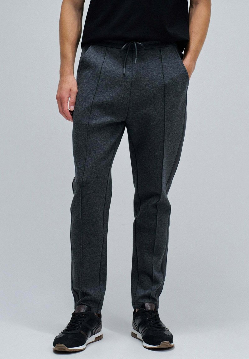 Graue Jogginghosen aus einem weichen, strukturierten Stoff, mit einem Kordelzugbund, schlanker Passform und kontrastierenden Seitennähten.
