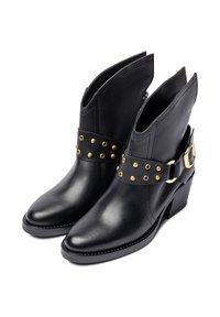 Zwarte leren enkellaarsjes met een goudkleurige, met studs versierde riem en gesp, een spits toelopende neus en een lage blokhak. Heeft uitsparingen aan de zijkanten voor extra design.